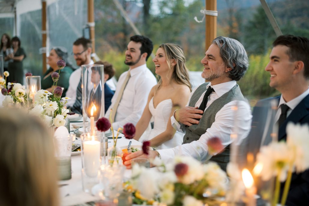 The newlyweds and guests laughing during toasts inside the reception tent at a Scribner’s Catskill Lodge wedding.