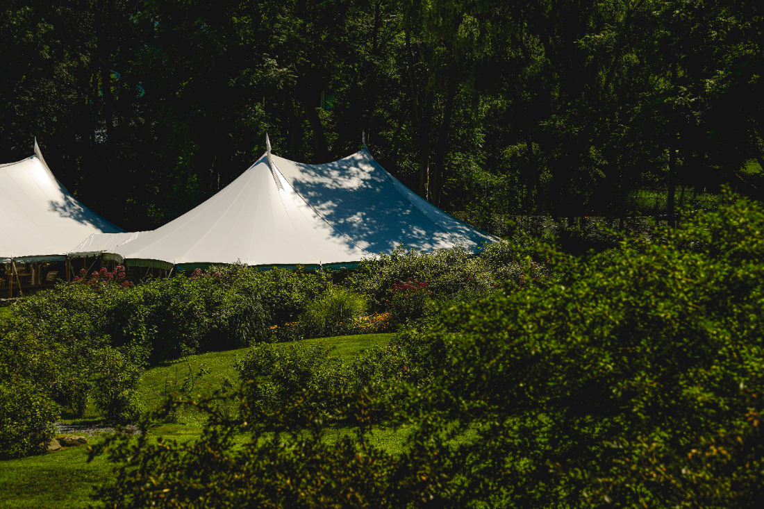 Sailcloth reception tent surrounded by lush greenery at a buttermilk falls inn wedding.