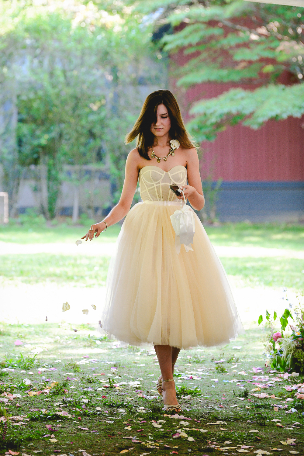 A woman in a soft tulle dress scattering petals down the aisle during a Buttermilk Falls Inn wedding ceremony.