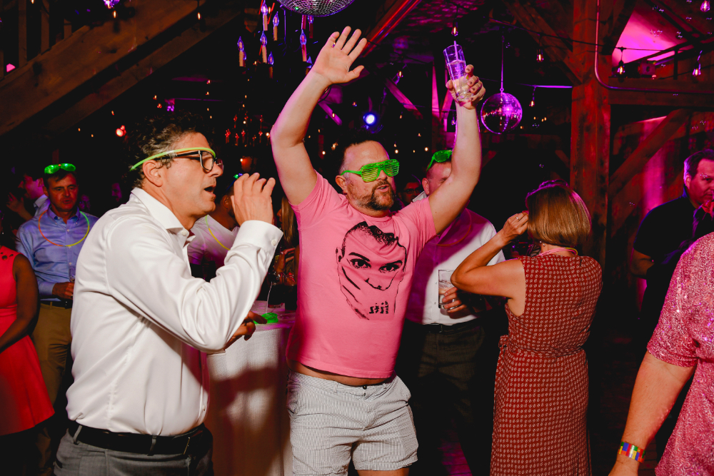 Friends laughing and dancing together on the glowing 80s-inspired dance floor.