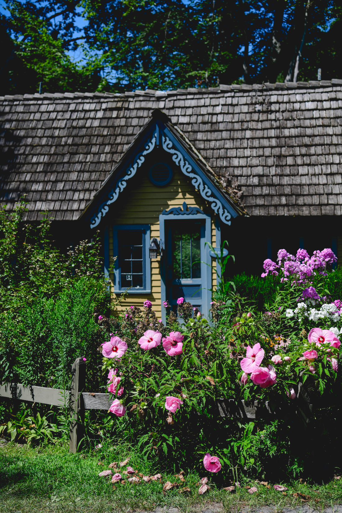 Charming yellow cottage with blooming pink flowers at the buttermilk falls inn wedding venue.