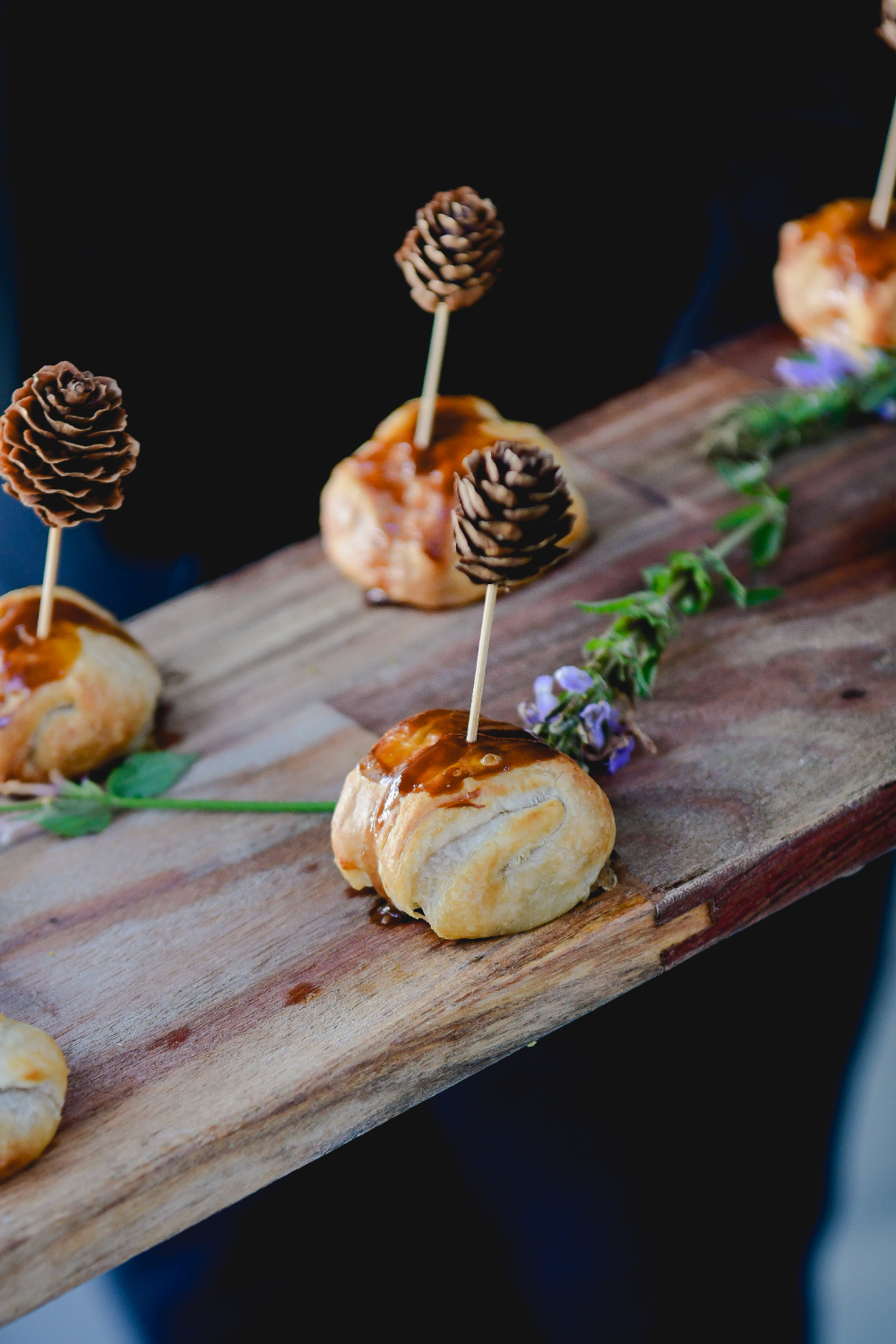 Small pastry appetizers decorated with miniature pinecone picks are presented at a Buttermilk Falls Inn wedding.