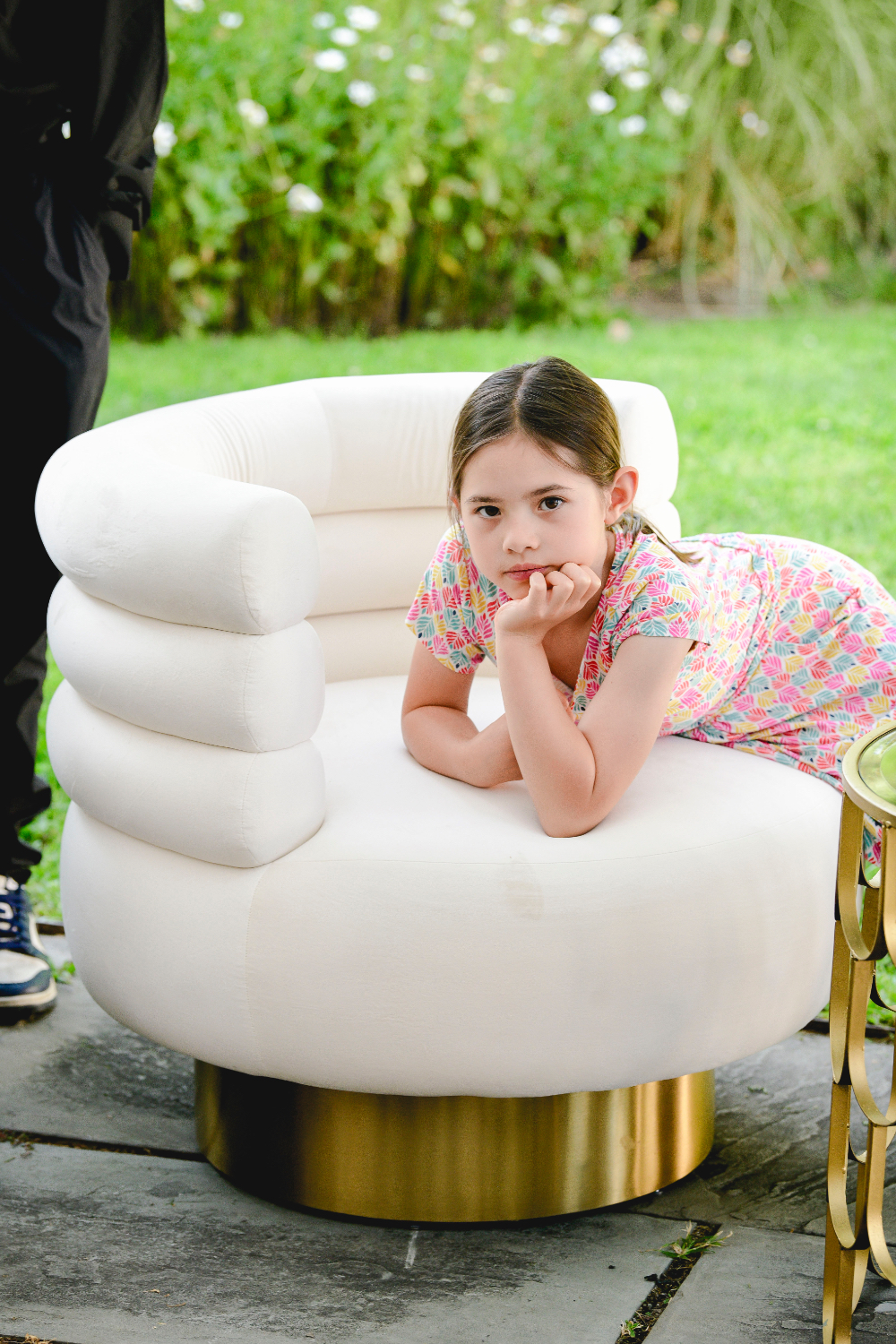 A young guest leans on a white and gold accent chair at a Buttermilk Falls Inn wedding reception.