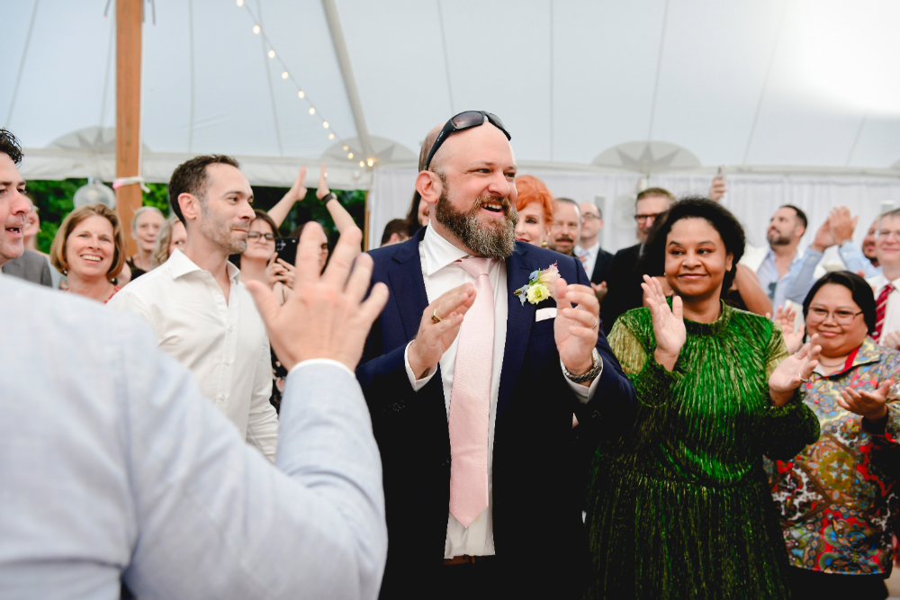 The couple dances together surrounded by cheering guests.