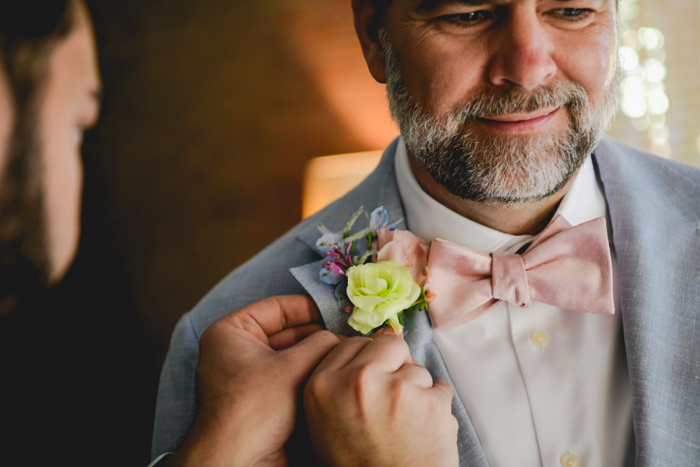 A groom’s pastel boutonniere is pinned to his light blue suit jacket during his Buttermilk Falls Inn wedding preparations.