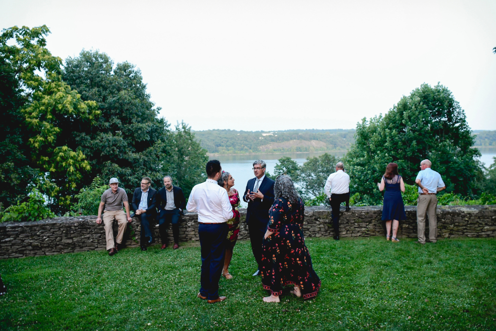 guests mingle on the grass outside of the tented reception area with beautiful views around them.