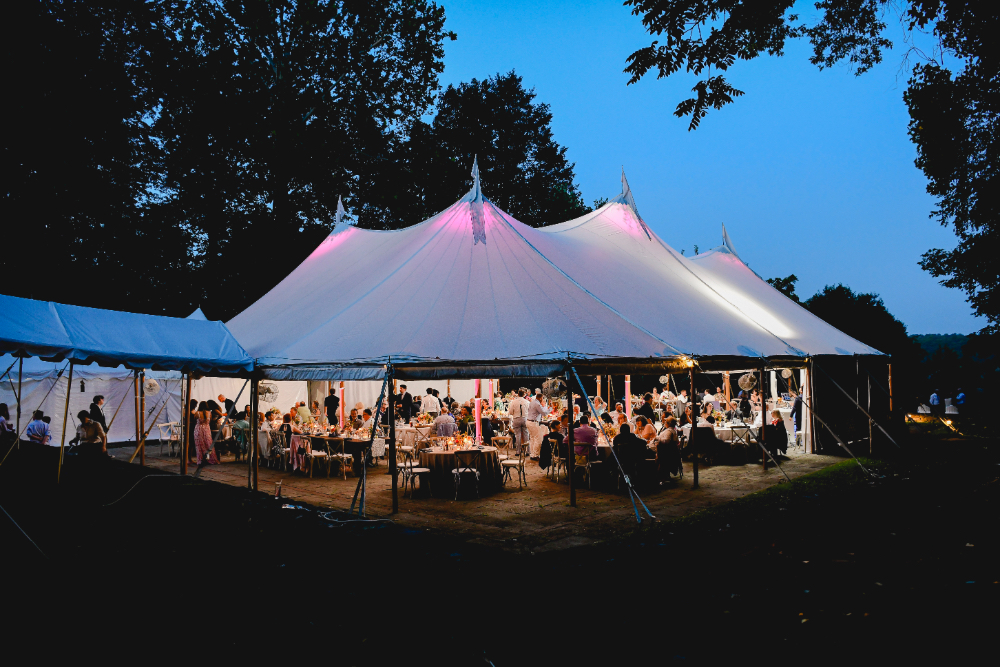 The reception tent glows warmly at night during a Buttermilk Falls Inn wedding.