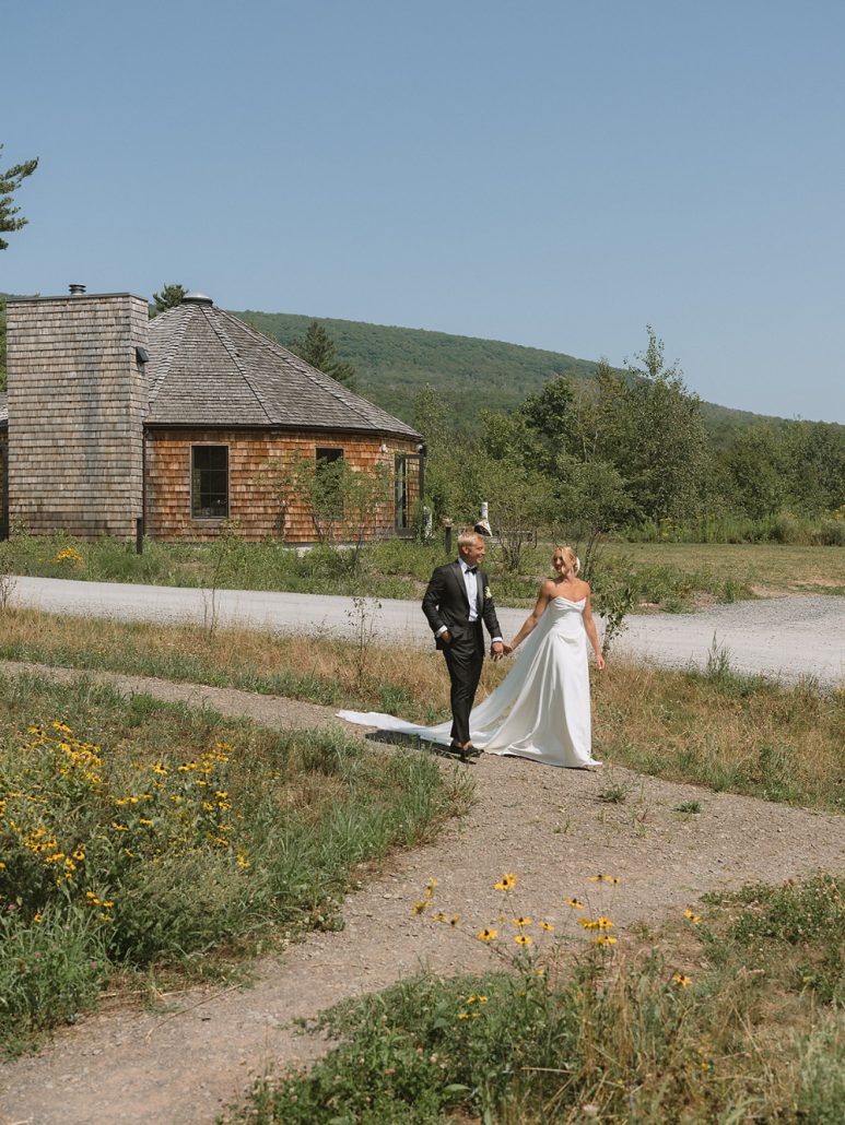 Couple walking along a mountain path near a rustic lodge, perfect inspiration for a multi day wedding in the outdoors