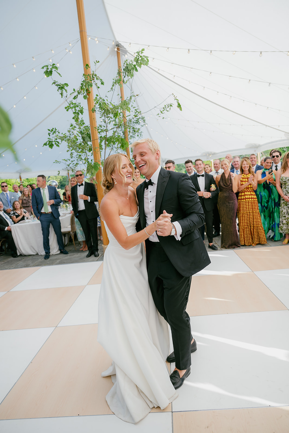 Bride and groom sharing their first dance under a sailcloth tent as guests cheer around them during a multi day wedding celebration