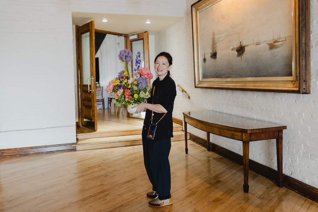 Full service wedding planner holding a large colorful floral arrangement during event setup.