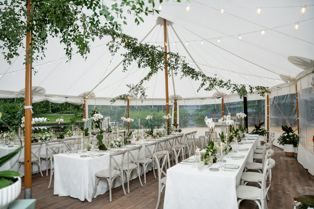 Luxury tented wedding reception with white florals and soft lighting, illustrating how to choose wedding vendors who execute refined outdoor events.