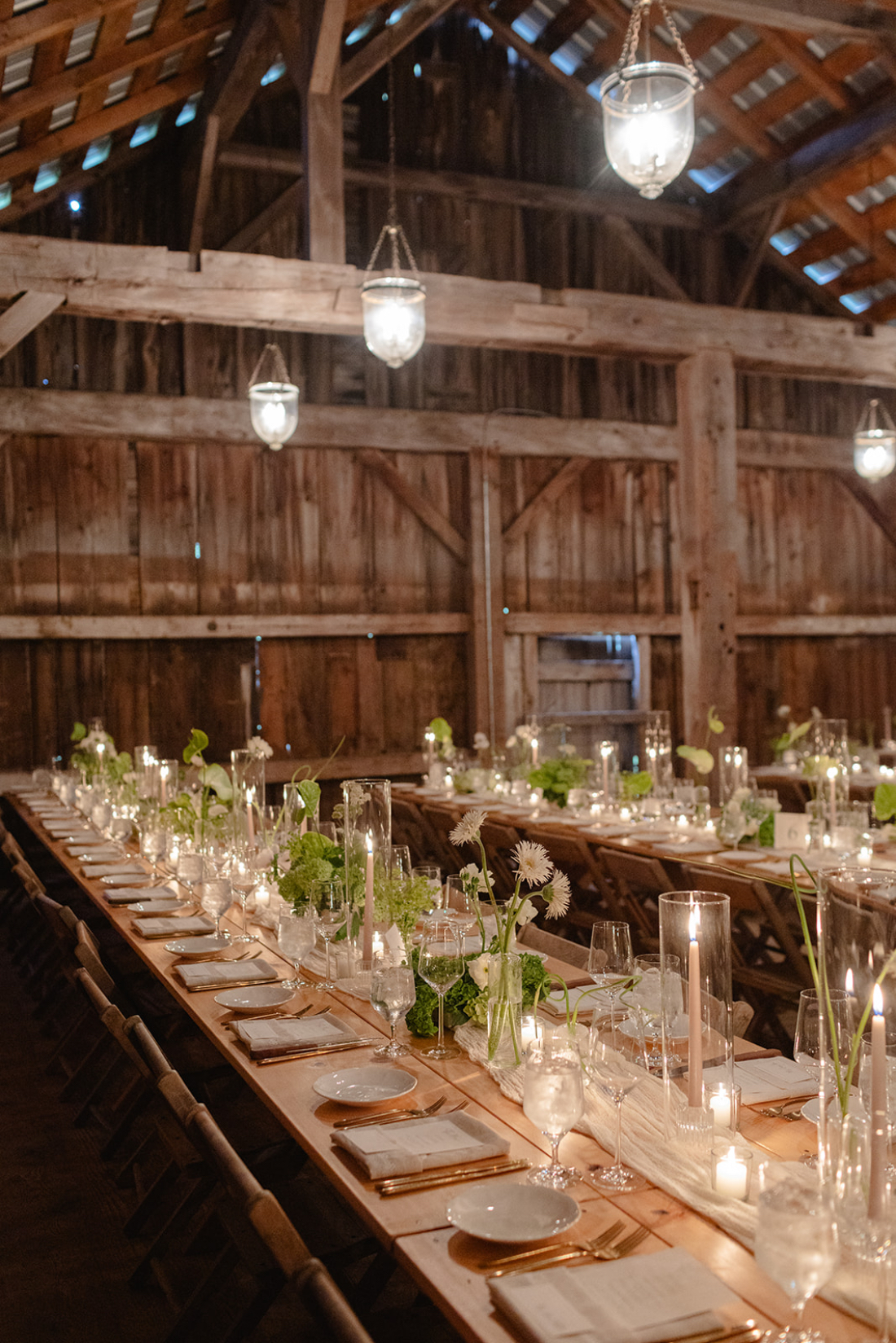 Rustic barn reception with long wooden tables and candlelight ambiance, a beautiful example of how to choose wedding vendors for warm, inviting spaces.