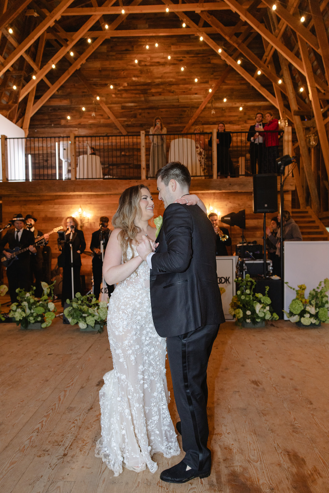 Couple sharing their first dance in a barn venue with live band and string lights, demonstrating how to choose wedding vendors who create unforgettable experiences.