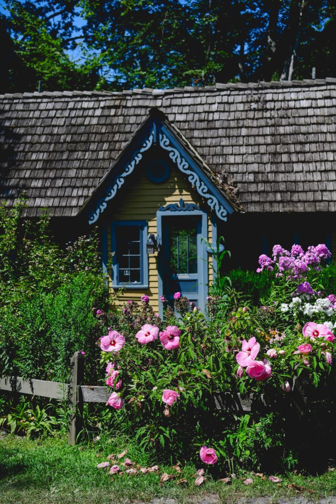 Quaint cottage with blooming pink flowers and lush greenery during a summer wedding weekend in the countryside.