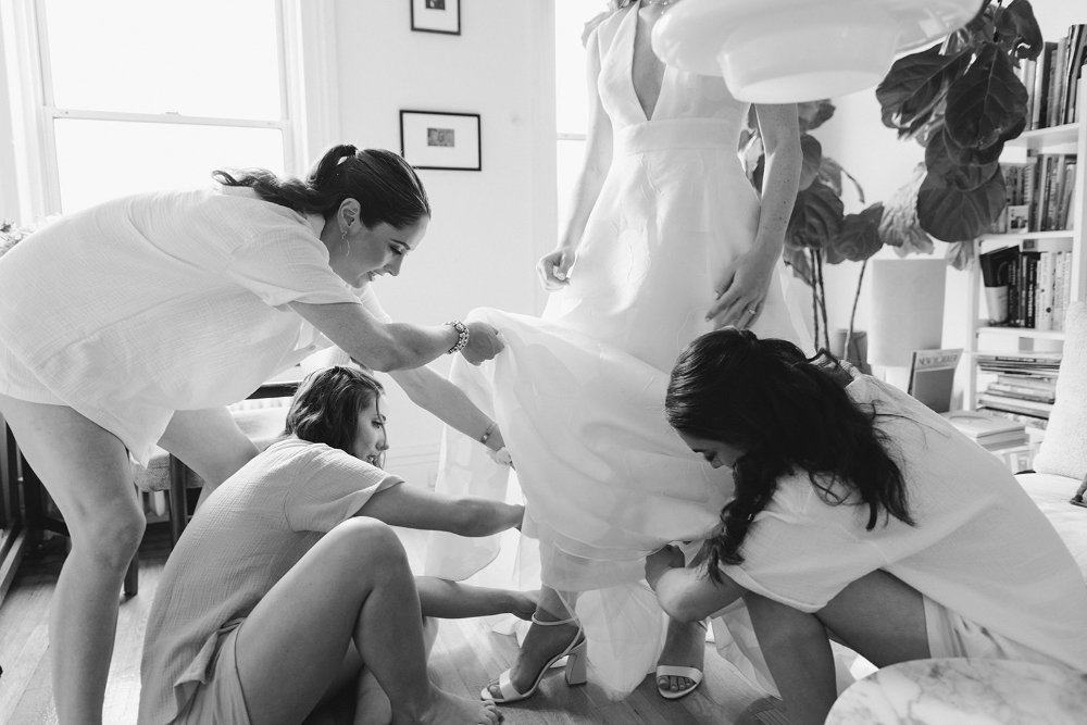 Bride getting ready with bridesmaids adjusting her gown before the ceremony
