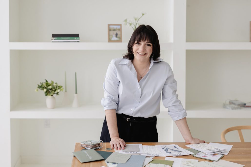 Luxury wedding planner reviewing invitation suites and wedding contracts at a clean, modern desk