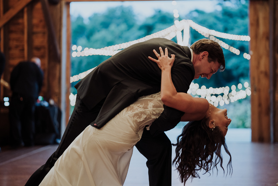 Couple sharing a romantic first dance in a warmly lit barn wedding venue