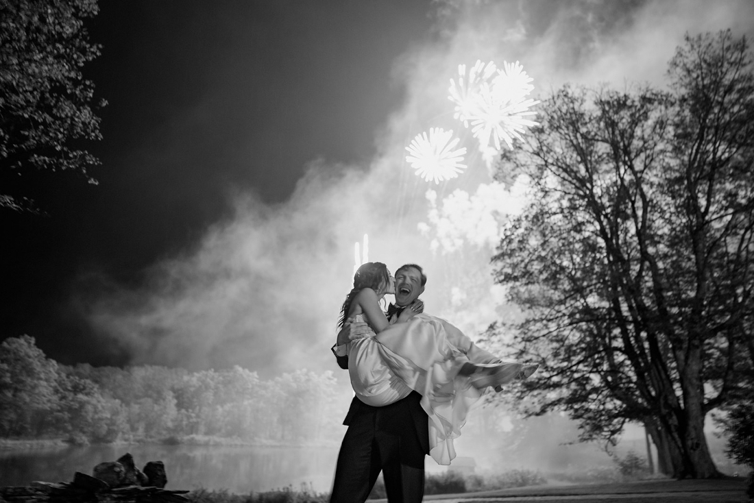 Newlyweds celebrating outdoors with fireworks at an elegant evening wedding reception