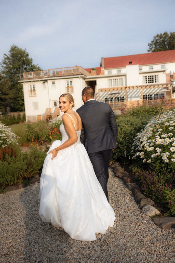 Bride and groom walking through a garden path at a luxury estate wedding venue