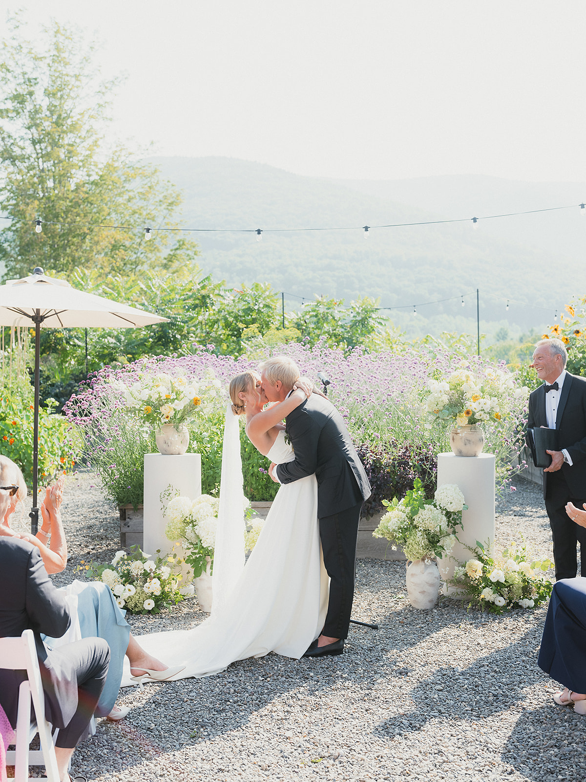 Outdoor mountain wedding ceremony with couple kissing surrounded by florals and scenic views, showcasing a moment an AI wedding planner can’t replicate