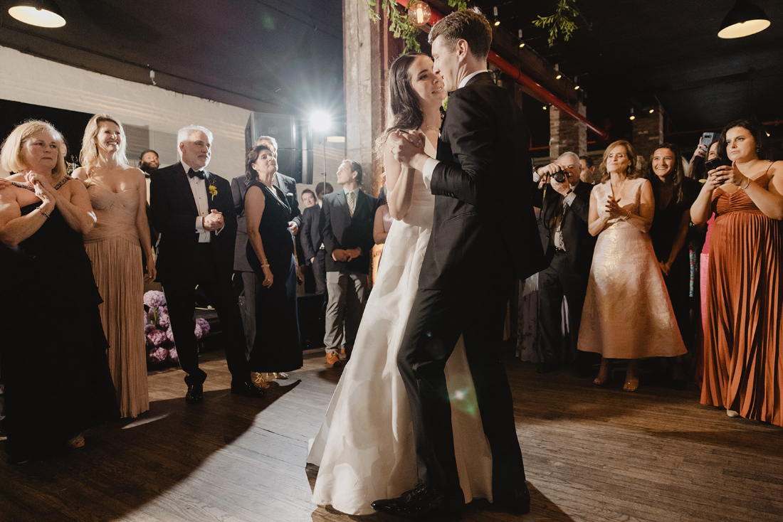 Romantic first dance in a dimly lit reception space with guests gathered around, highlighting the atmosphere beyond an AI wedding planner