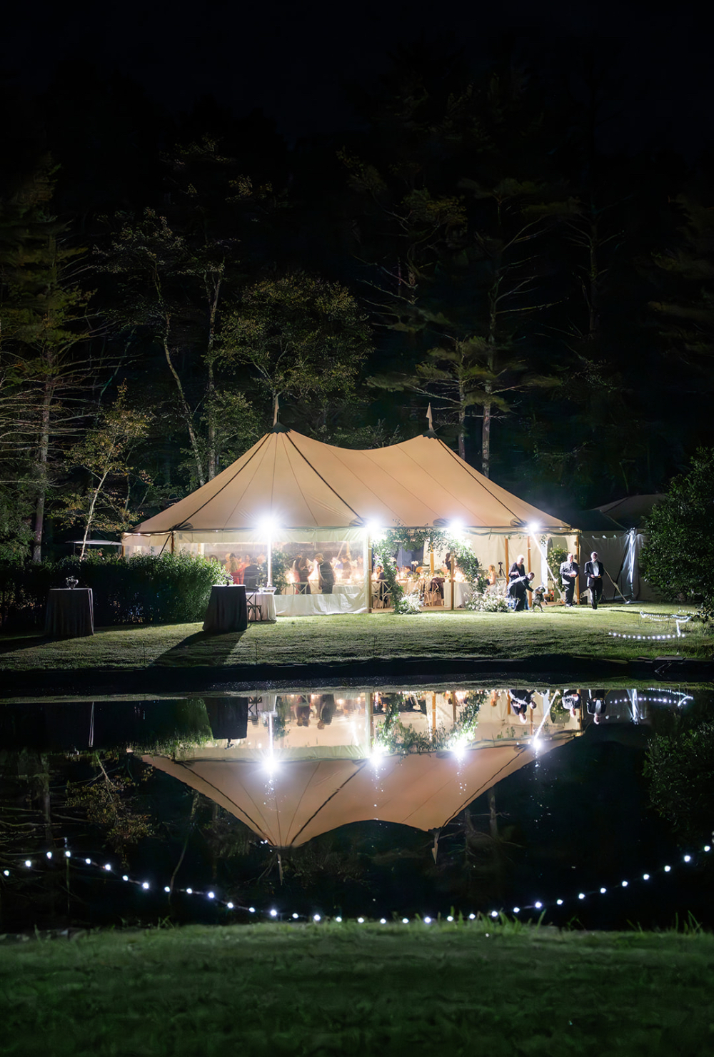 Sailcloth tent glowing beside a reflecting pond at a private estate home wedding in New England