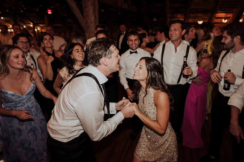 Couple dancing joyfully surrounded by guests on a lively reception dance floor