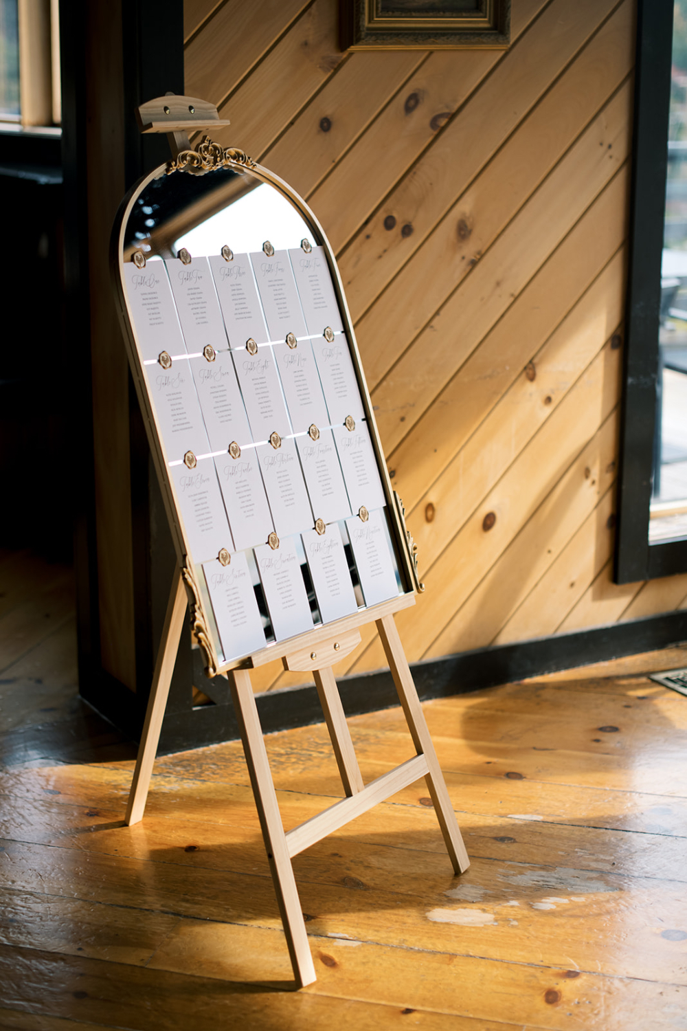 Seating chart displayed on a mirror with escort cards in a refined indoor setting, highlighting wedding planner responsibilities