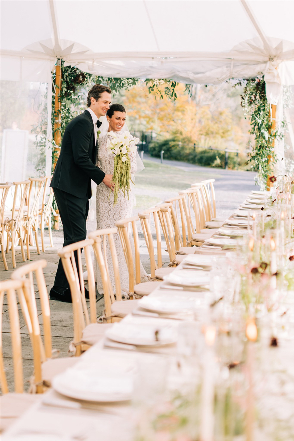 Newlyweds walking into reception space with long tables and elegant place settings