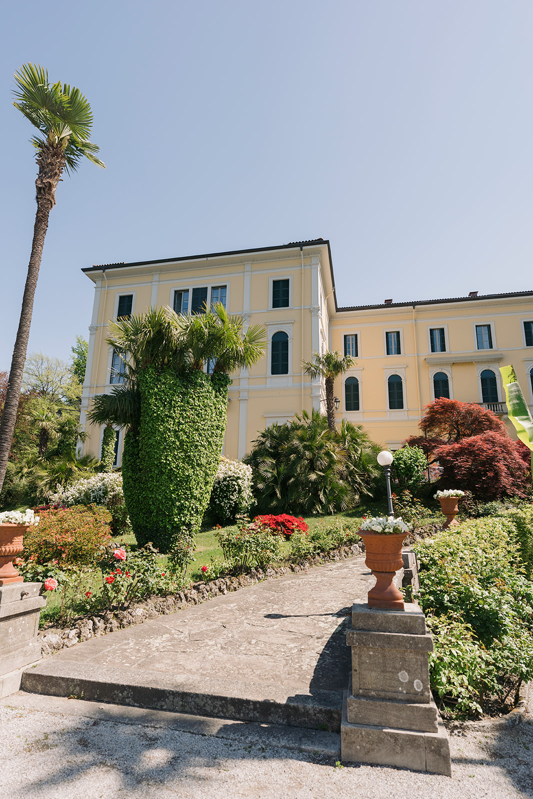 Elegant historic villa surrounded by manicured gardens and palm trees on the shores of Lake Como.