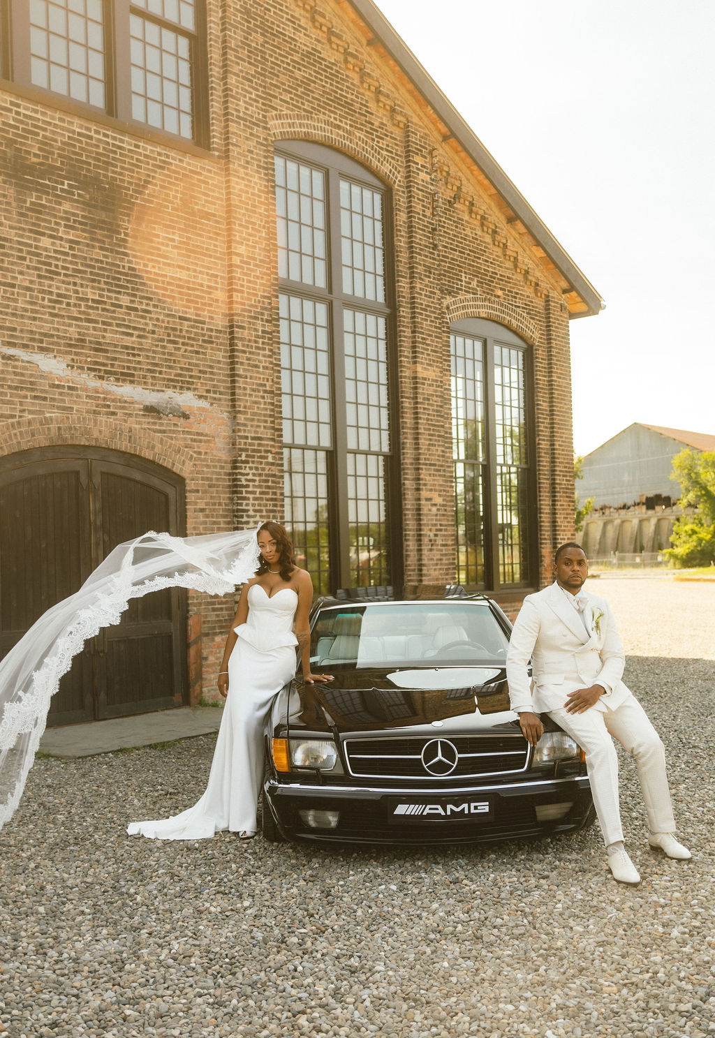 Bride and groom posing with a vintage Mercedes outside an industrial wedding venue discovered through venue scouting in the Hudson Valley.