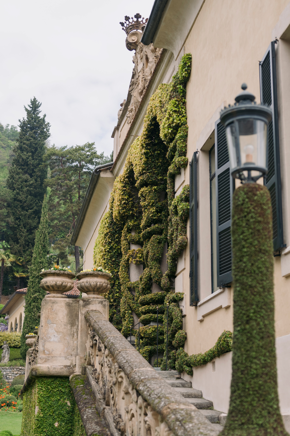 Formal Italian gardens with cypress trees, stone statues, and vibrant spring flowers at a Villa del Balbianello wedding.