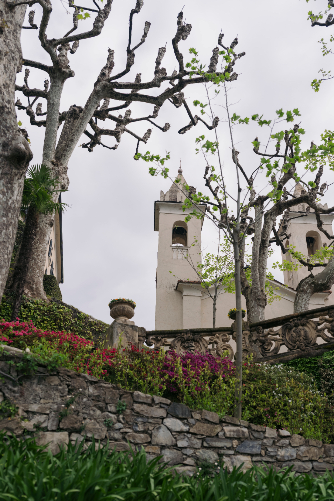 Historic church towers and sculpted trees overlooking the gardens of a Villa del Balbianello wedding venue on Lake Como.