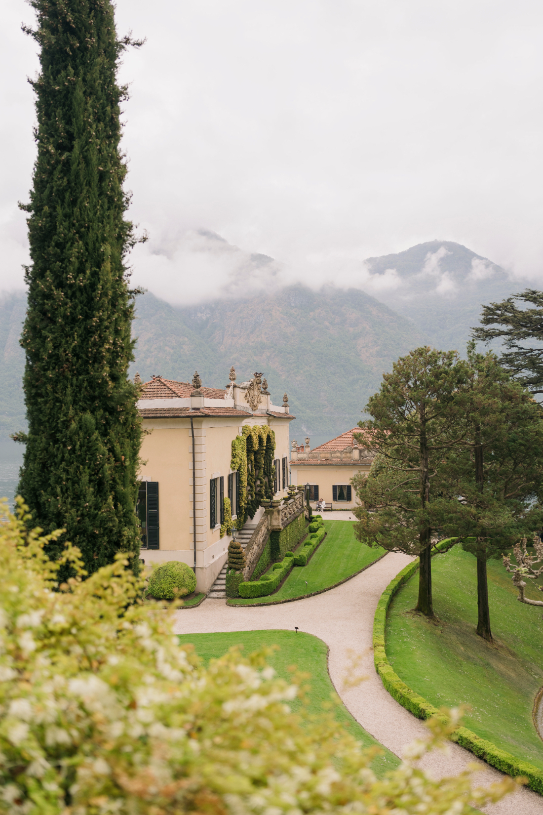 Elegant villa, formal Italian gardens, and mist-covered mountains at a Villa del Balbianello wedding on Lake Como.