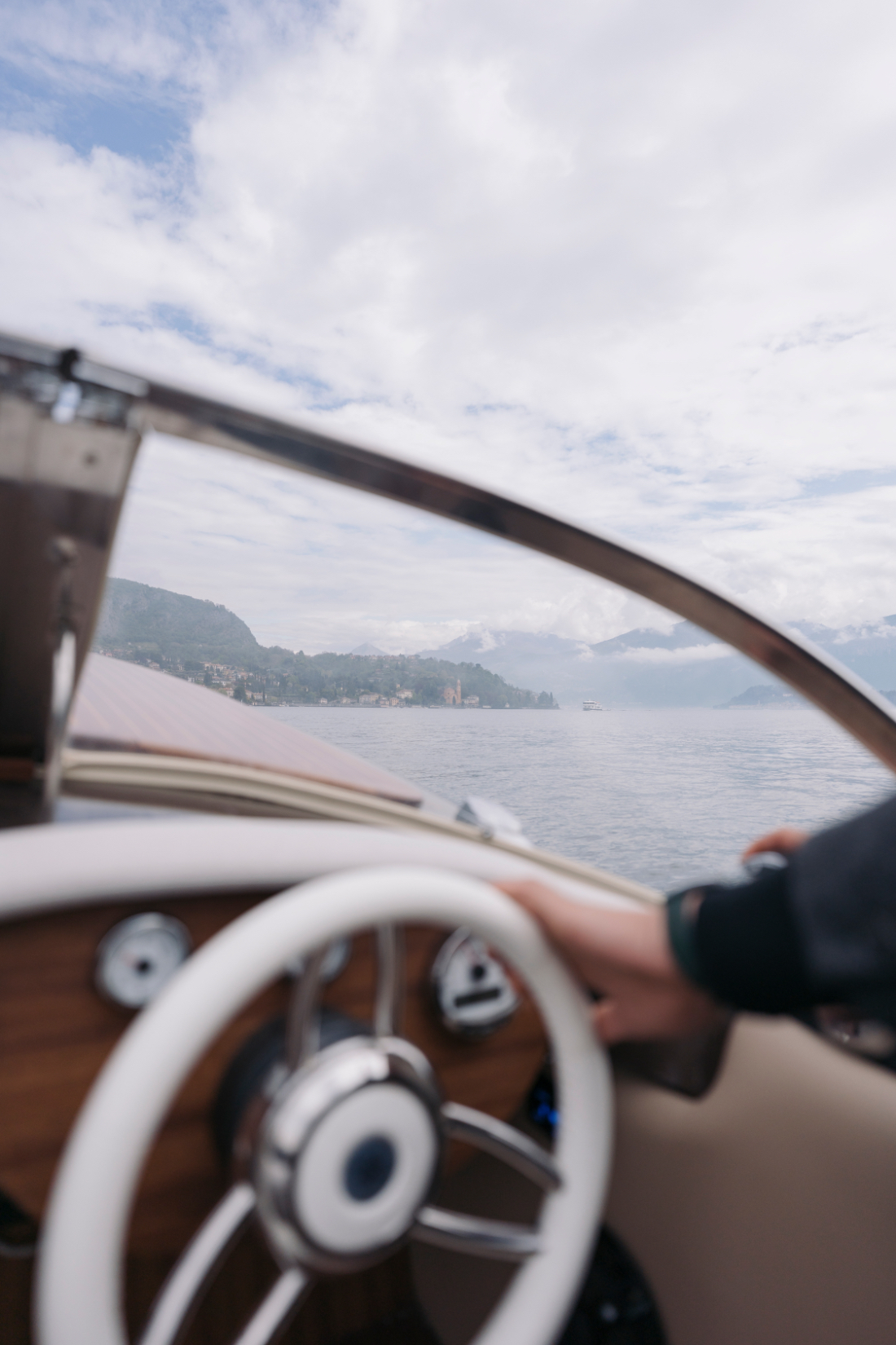 View from a classic wooden boat crossing Lake Como toward a Villa del Balbianello wedding venue.