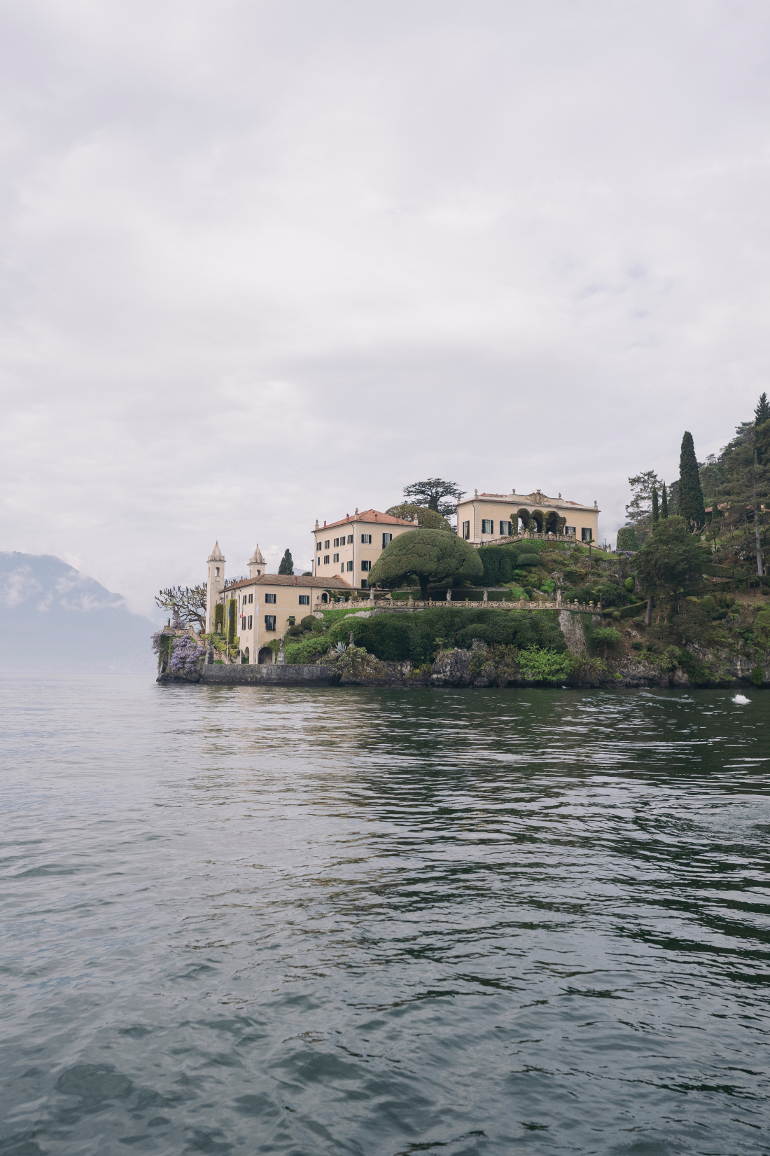 Elegant lakeside view of Villa del Balbianello with manicured gardens and historic architecture reflected on Lake Como.