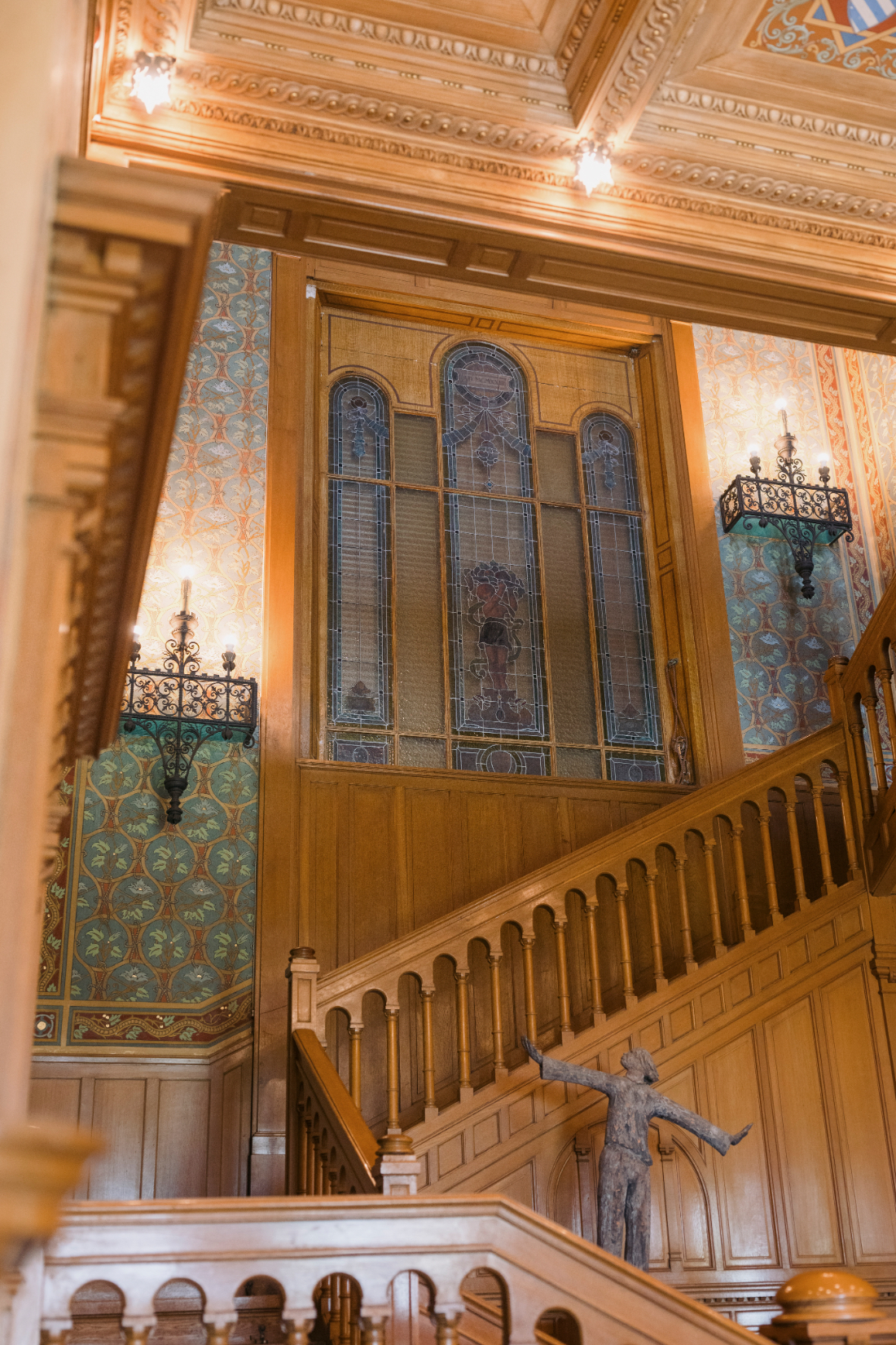 Grand wooden staircase with stained glass windows and ornate painted walls inside a historic Italian villa overlooking Lake Como.