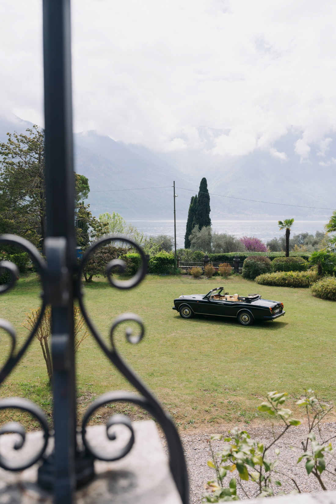 View across the gardens toward Lake Como with a vintage convertible parked on the lawn
