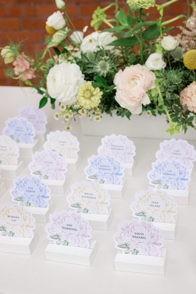 Floral-inspired escort cards surrounded by romantic garden flowers at Mirbeau Beacon