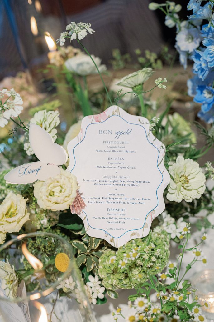 Floral dinner menu and butterfly place card nestled into garden-inspired flowers at Mirbeau Beacon
