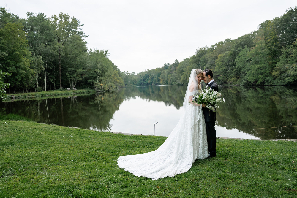 Newlyweds sharing a quiet moment beside a scenic lake after their outdoor wedding ceremony.